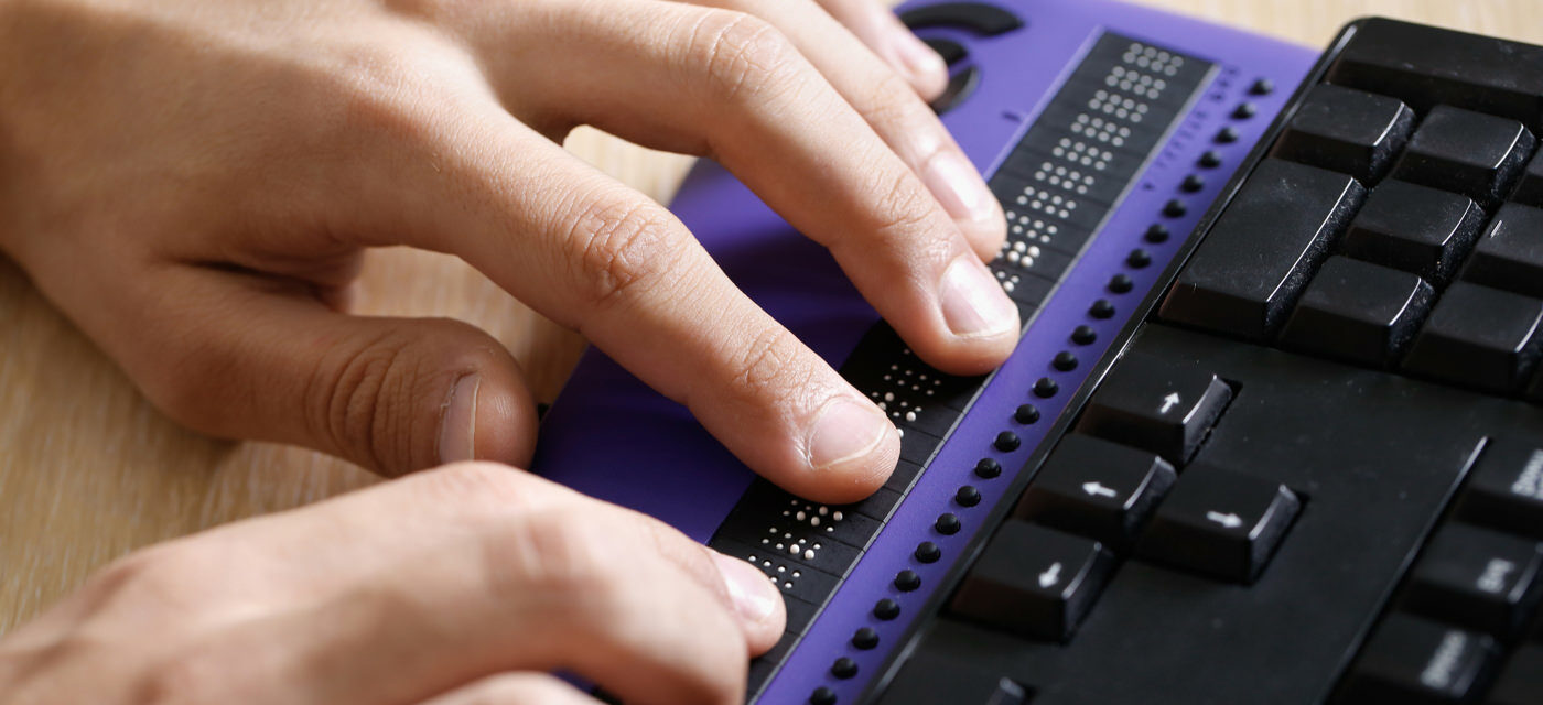 Close up of two hands on a Braille keyboard