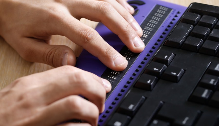 Close up of two hands on a Braille keyboard