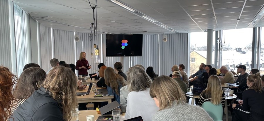 A room full of people with me in the background standing in front of a big TV screen with the Figma logotype on it.